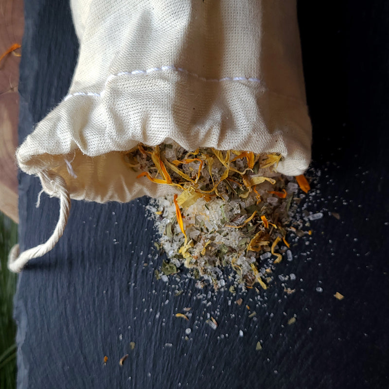 Herbal Foot Soak open bag contents spilling on slate, crystals, calendula petals, peppermint leaves