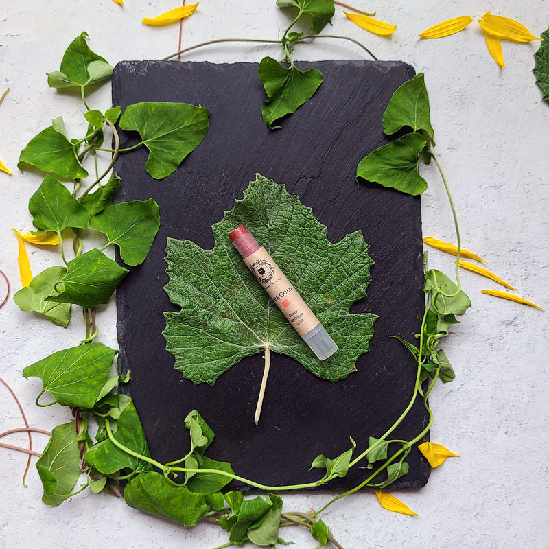 Opened Rose Gold flat lay on leaves and slatel